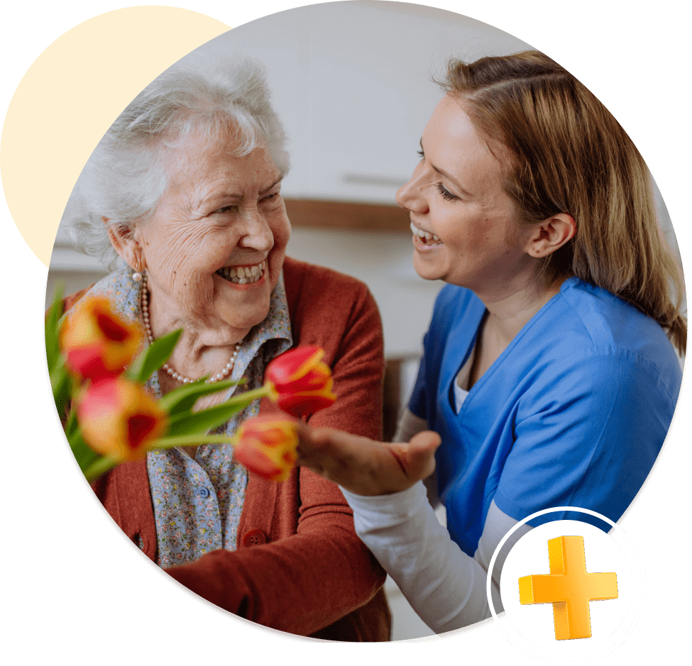 Elderly woman and nurse with flowers smiling.